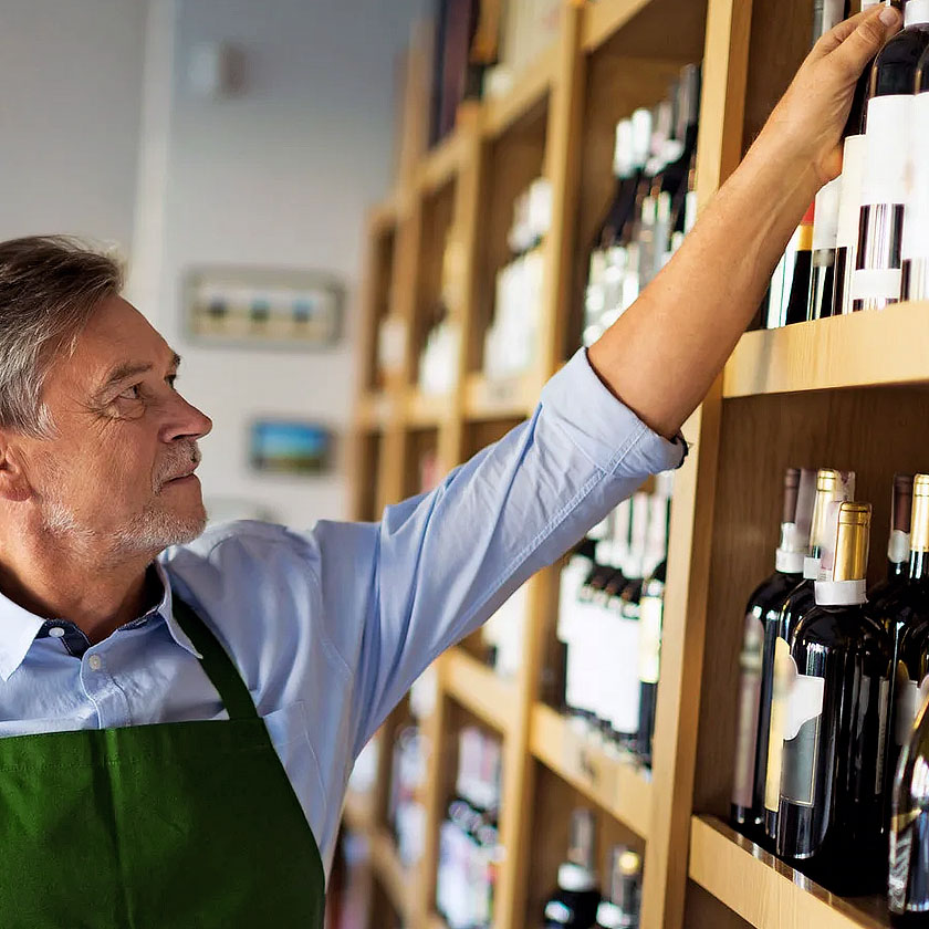 Man reaching for wine bottle on shelf